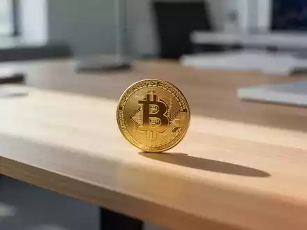 Eine einzelne physische Bitcoin-Münze auf einem minimalistischen Schreibtisch bei natürlichem Tageslicht. - Foto: über boerse-global.de