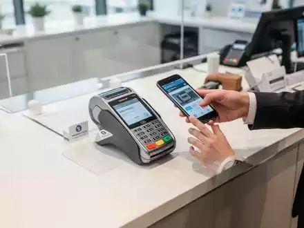 Eine Person bezahlt kontaktlos an einem modernen, digitalen Kassenterminal in einem hellen Geschäftsumfeld. - Foto: über boerse-global.de