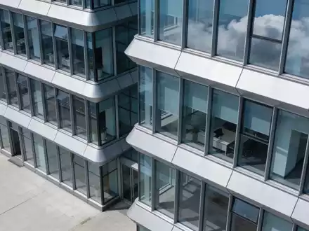 Moderne Glasfassade eines Bürogebäudes bei bewölktem Himmel. - Foto: über boerse-global.de