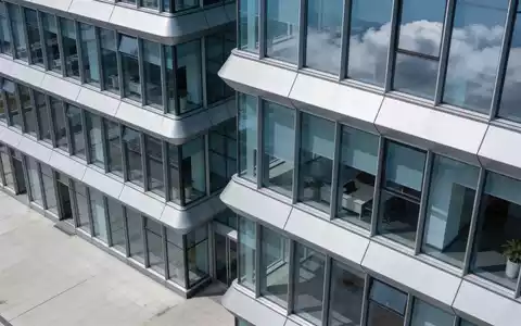 Moderne Glasfassade eines Bürogebäudes bei bewölktem Himmel. - Foto: über boerse-global.de