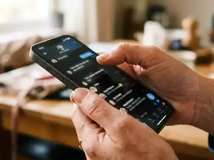 Nahaufnahme einer Hand, die ein Smartphone hält, während sie durch eine Messenger-App auf dem Display navigiert. - Foto: über boerse-global.de
