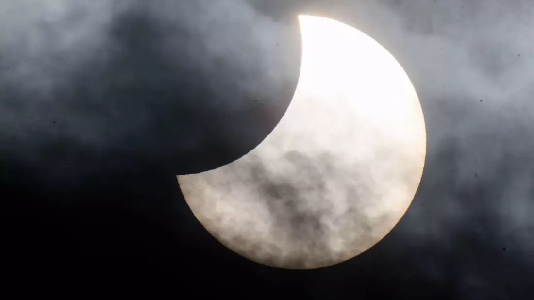 Eine partielle Sonnenfinsternis ist zwischen Wolken am Himmel zu sehen. (Archivbild) - Bild: Julian Stratenschulte/dpa