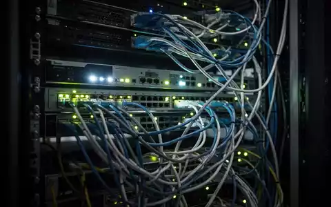 Dunkler Serverraum mit leuchtenden Netzwerkkabeln und technischer Infrastruktur. - Foto: über boerse-global.de
