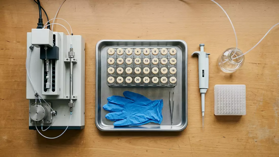 Flatlay-Arrangement rund um Chromatograph mit passenden Requisiten von oben, neutral