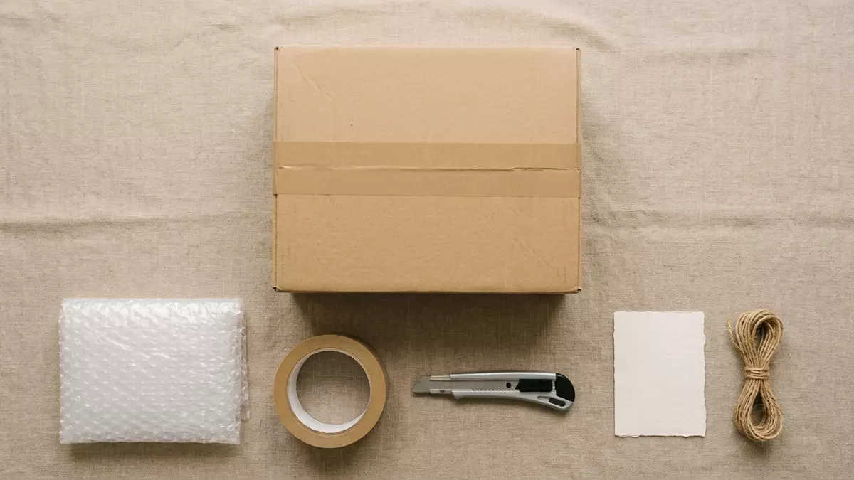Flatlay-Arrangement rund um Versandpaket mit passenden Requisiten von oben, neutral