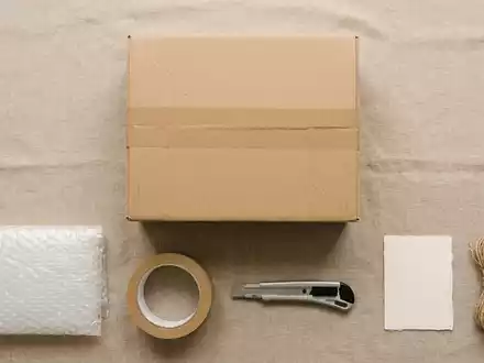 Flatlay-Arrangement rund um Versandpaket zum Thema DHL Paket, ISIN DE0005552004, weiches Oberlicht - Foto: THN