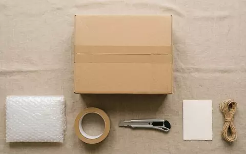 Flatlay-Arrangement rund um Versandpaket zum Thema DHL Paket, ISIN DE0005552004, weiches Oberlicht - Foto: THN