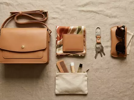 Flatlay-Arrangement rund um Lederhandtasche zum Thema Michael Kors Handtasche, ISIN US14040H1059, weiches Oberlicht - Foto: THN
