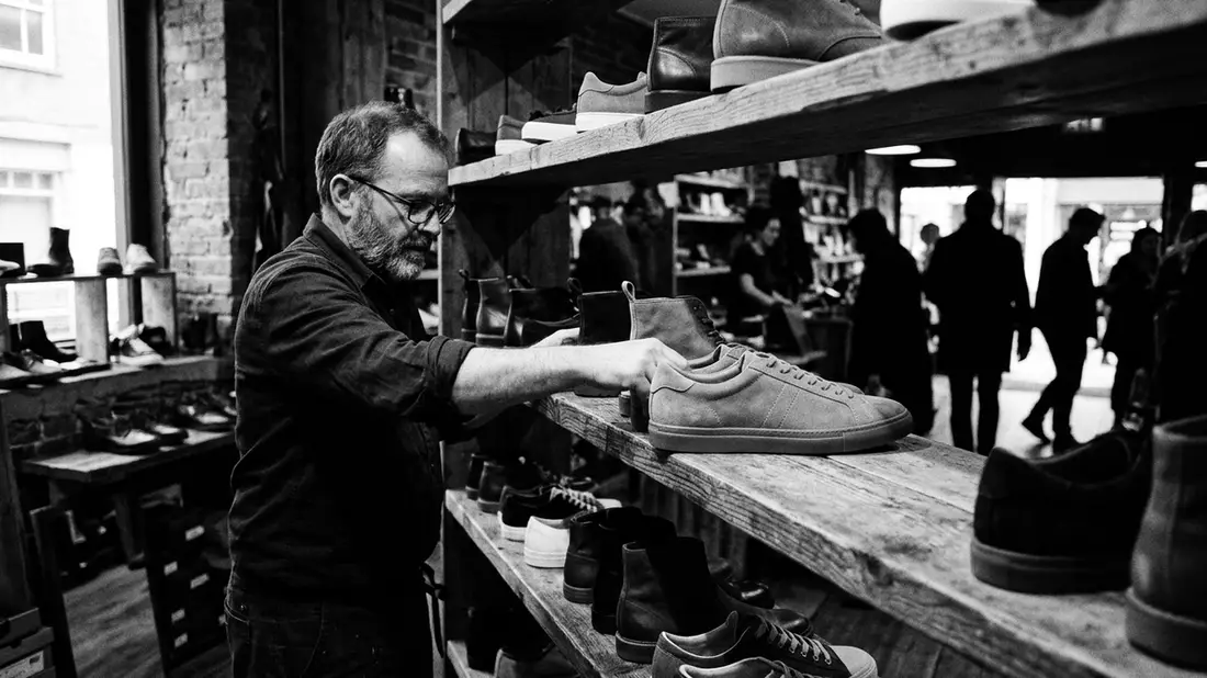Schwarzweiss-Reportagebild mit Retro-Sneaker in dokumentarischer Arbeitsumgebung