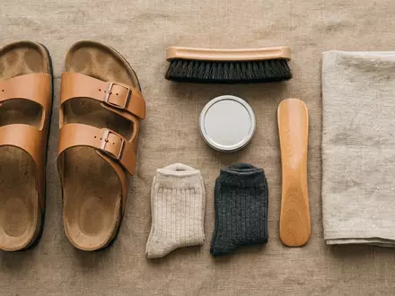 Flatlay-Arrangement rund um Zweiriemensandalen zum Thema Birkenstock Arizona, ISIN JE00BS44BN30, weiches Oberlicht - Foto: THN