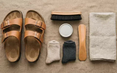Flatlay-Arrangement rund um Zweiriemensandalen zum Thema Birkenstock Arizona, ISIN JE00BS44BN30, weiches Oberlicht - Foto: THN