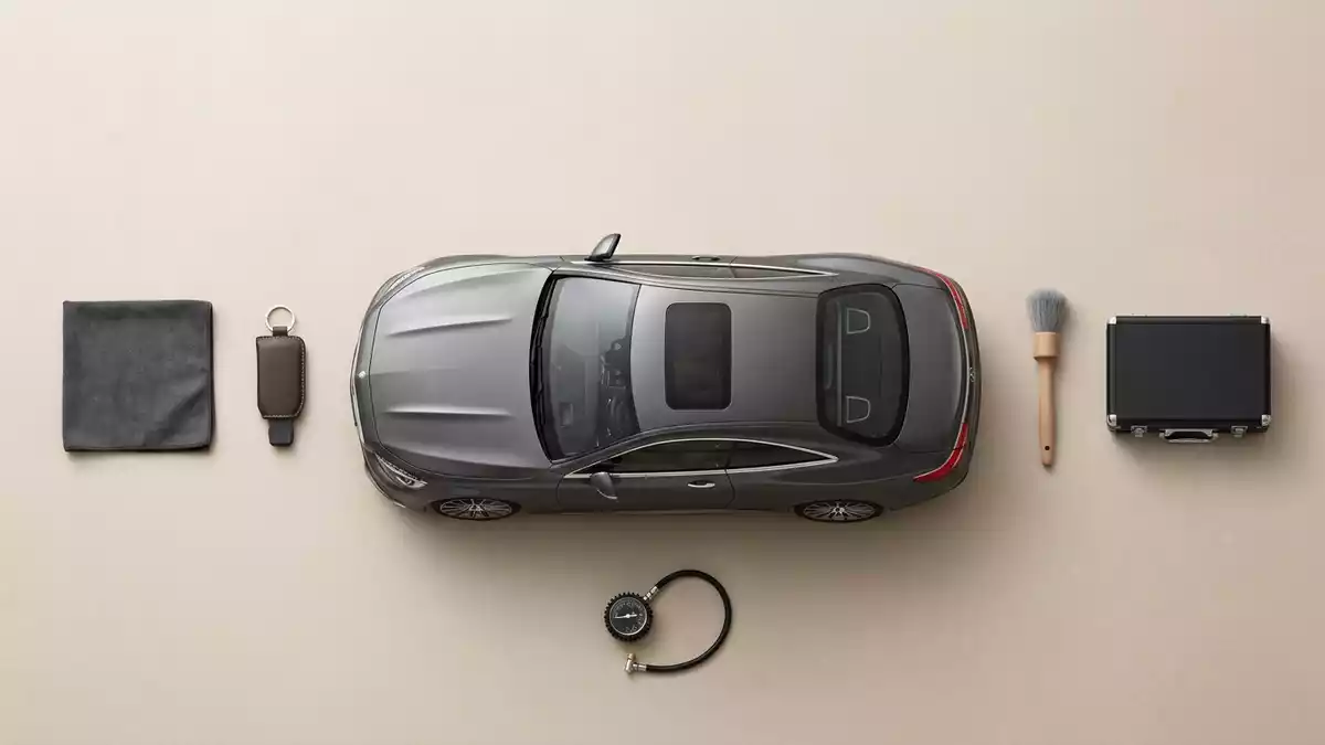Flatlay-Arrangement rund um Sportcoupé mit passenden Requisiten von oben, neutral
