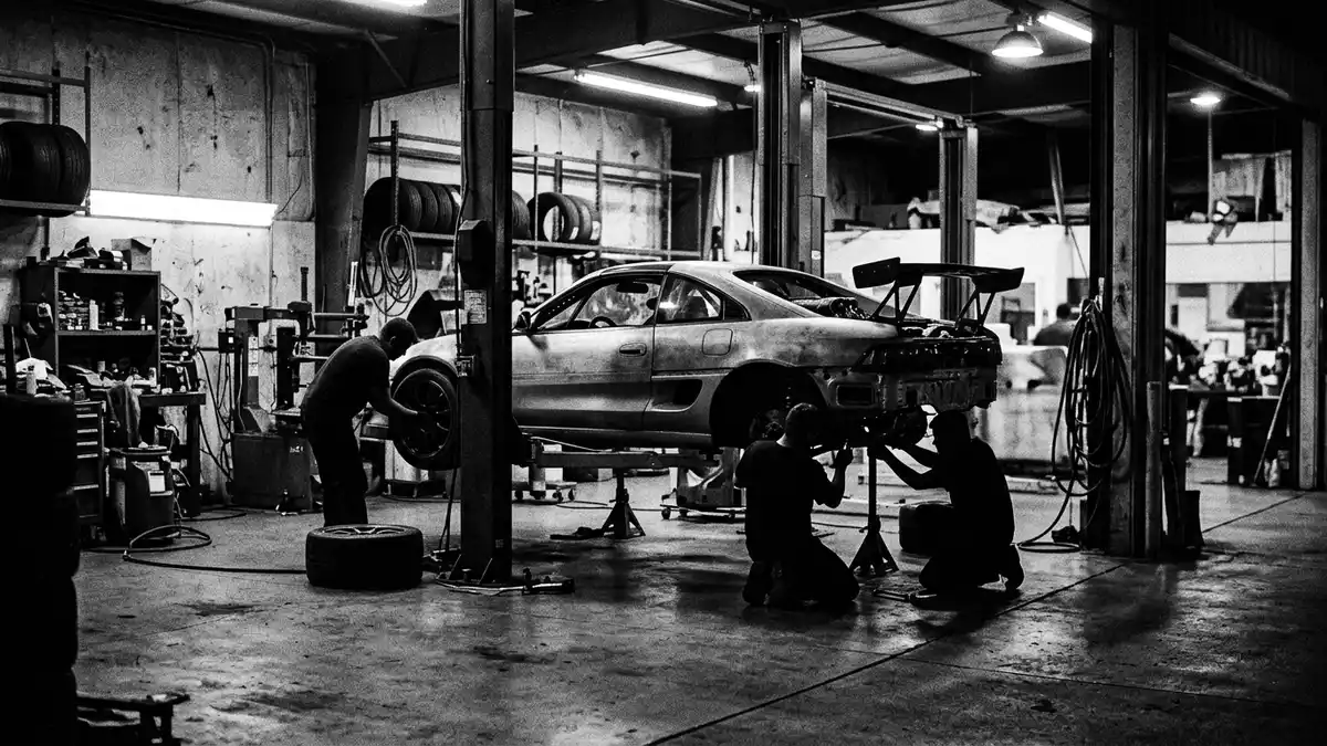 Schwarzweiss-Reportagebild mit Sportcoupé in dokumentarischer Arbeitsumgebung, neutral