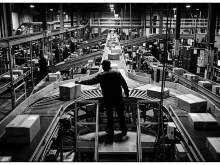 Schwarzweiss-Reportage mit Paketsortierung zum Thema Kühne+Nagel Tracking, ISIN CH0044328745, hoher Kontrast, sachlich dargestellt - Foto: THN