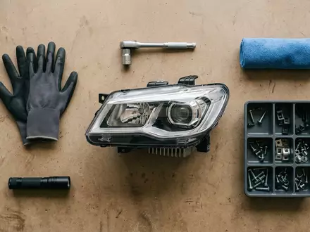 Flatlay-Arrangement rund um Autoscheinwerfer zum Thema Hella Scheinwerfer, ISIN DE000A13SX22, weiches Oberlicht - Foto: THN