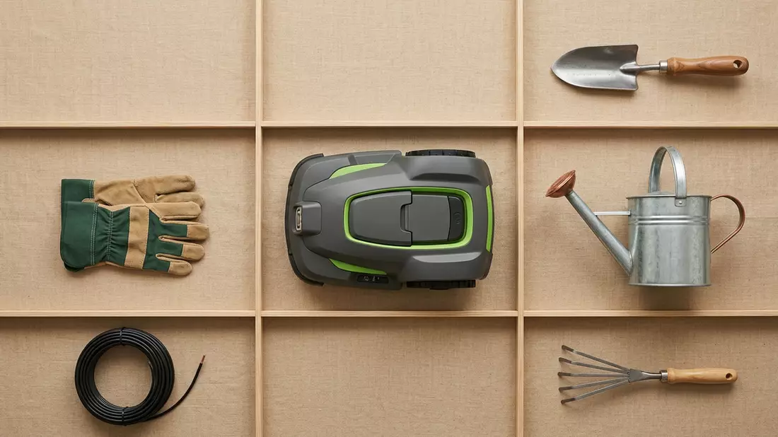 Flatlay-Arrangement rund um Mähroboter mit passenden Requisiten von oben, neutral