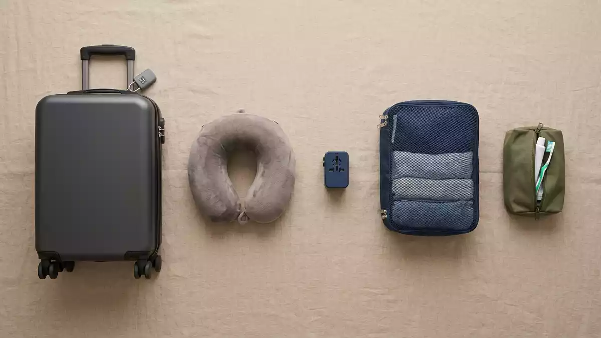 Flatlay-Arrangement rund um Handgepäckkoffer mit passenden Requisiten von oben