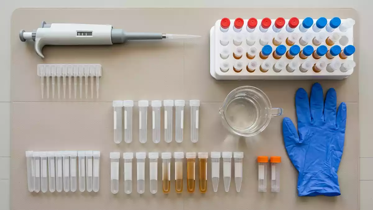 Flatlay-Arrangement rund um Laborpipette mit passenden Requisiten von oben, neutral