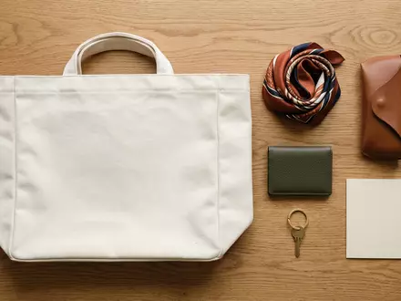 Flatlay-Arrangement rund um Stofftasche zum Thema Dior Book Tote, ISIN FR0000121014, weiches Oberlicht - Foto: THN
