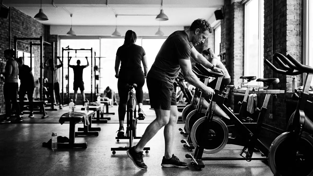 Schwarzweiss-Reportagebild mit Heimtrainer in dokumentarischer Arbeitsumgebung