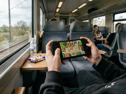 Fotorealistische Aufnahme von Handheld-Konsole auf Reisen zum Thema Nintendo Switch OLED, ISIN JP3756600007, natuerliches Licht - Foto: THN