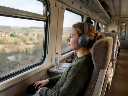 Fotorealistische Aufnahme von Over-Ear-Kopfhörer auf Reisen zum Thema Sennheiser Momentum 4, ISIN CH0012549785, natuerliches Licht - Foto: THN