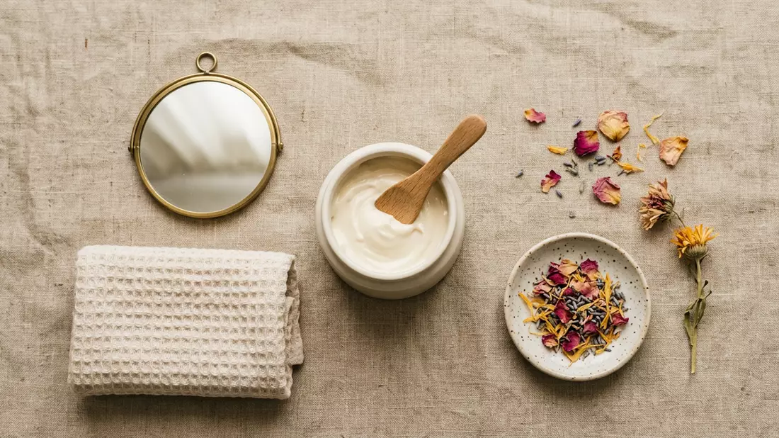 Flatlay-Arrangement rund um Gesichtscreme mit passenden Requisiten von oben, neutral