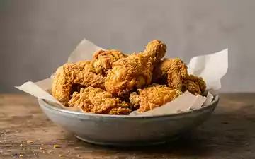 Fotorealistische Studioaufnahme von Frittiertes Hähnchen zum Thema KFC Bucket, ISIN US9884981013, klare Lichtfuehrung - Foto: THN