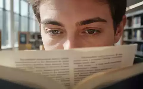 Nahaufnahme einer Person, die in einem hellen Raum konzentriert in einem Buch liest, Fokus auf die Augenpartie. - Foto: über boerse-global.de