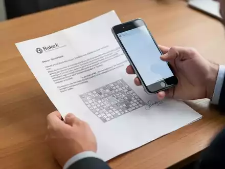 Eine Person hält ein Smartphone über einen QR-Code auf einem Bankbrief, um diesen zu scannen. - Foto: über boerse-global.de