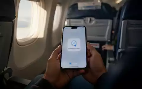 Passagier hält ein Smartphone in einer Flugzeugkabine, während das Bord-WLAN-System im Hintergrund aktiv ist. - Foto: über boerse-global.de