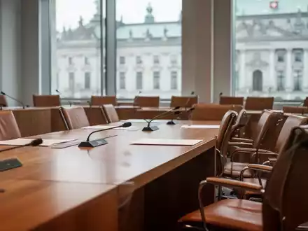 Moderner Sitzungssaal im Schweizer Parlamentsgebäude mit leeren Stühlen und Holztischen bei natürlichem Tageslicht. - Foto: über boerse-global.de