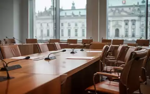 Moderner Sitzungssaal im Schweizer Parlamentsgebäude mit leeren Stühlen und Holztischen bei natürlichem Tageslicht. - Foto: über boerse-global.de