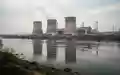 Kernkraftwerk Paks an der Donau mit Blick auf die Reaktorblöcke und den Fluss bei bewölktem Himmel. - Foto: über boerse-global.de