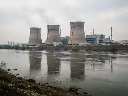 Kernkraftwerk Paks an der Donau mit Blick auf die Reaktorblöcke und den Fluss bei bewölktem Himmel. - Foto: über boerse-global.de