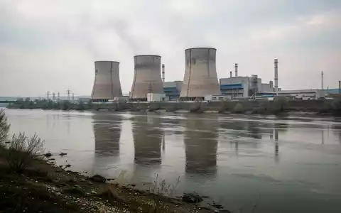Kernkraftwerk Paks an der Donau mit Blick auf die Reaktorblöcke und den Fluss bei bewölktem Himmel. - Foto: über boerse-global.de