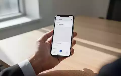 Eine Person hält ein Smartphone in einer Hand, das eine mobile Banking-App in einer hellen, modernen Büroumgebung anzeigt. - Foto: über boerse-global.de