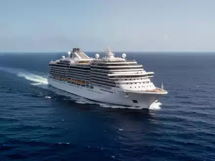 Ein großes weißes Kreuzfahrtschiff auf dem offenen blauen Ozean bei klarem Tageslicht. - Foto: über boerse-global.de
