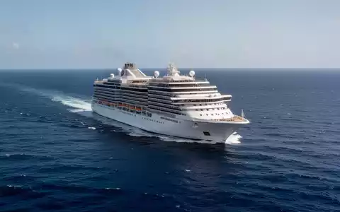 Ein großes weißes Kreuzfahrtschiff auf dem offenen blauen Ozean bei klarem Tageslicht. - Foto: über boerse-global.de