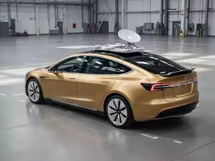 Ein goldenes autonomes Cybercab mit integrierter Starlink-Antenne auf dem Boden einer modernen Fabrikhalle. - Foto: über boerse-global.de