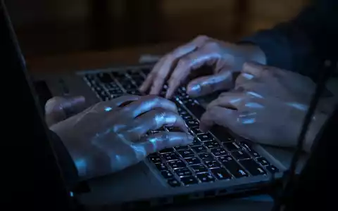Nahaufnahme einer Person, die in einem abgedunkelten Raum an einem Laptop arbeitet, beleuchtet durch das Licht des Bildschirms. - Foto: über boerse-global.de