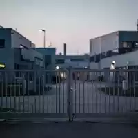 Geschlossenes Industrietor vor einer modernen Fabrikanlage in Bayern bei Dämmerung. - Foto: über boerse-global.de