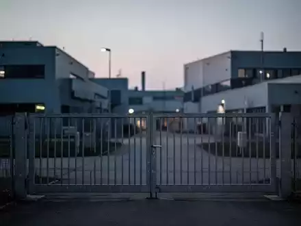 Geschlossenes Industrietor vor einer modernen Fabrikanlage in Bayern bei Dämmerung. - Foto: über boerse-global.de