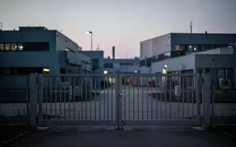 Geschlossenes Industrietor vor einer modernen Fabrikanlage in Bayern bei Dämmerung. - Foto: über boerse-global.de