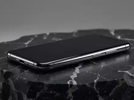 Ein hochwertiges, modernes Smartphone auf einer dunklen, texturierten Oberfläche in einer professionellen Studioaufnahme. - Foto: über boerse-global.de