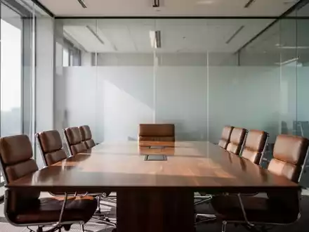 Ein moderner, leerer Konferenzraum mit Glastrennwänden und einem Holztisch in einer professionellen Büroumgebung. - Foto: über boerse-global.de