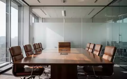 Ein moderner, leerer Konferenzraum mit GlastrennwĂ€nden und einem Holztisch in einer professionellen BĂŒroumgebung. - Foto: ĂŒber boerse-global.de