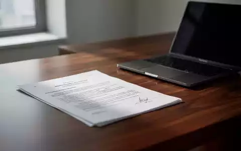 Ein minimalistischer Schreibtisch in einer Anwaltskanzlei mit einem Laptop und Dokumenten in weichem Tageslicht. - Foto: über boerse-global.de
