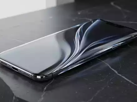 Ein rahmenloses Smartphone mit gewölbtem Glasgehäuse auf einer dunklen, polierten Oberfläche. - Foto: über boerse-global.de