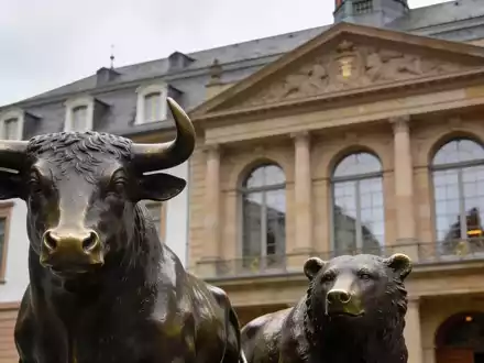 Die Fassade der Frankfurter Börse mit den Statuen von Bulle und Bär vor einem bewölkten Himmel. - Foto: über boerse-global.de